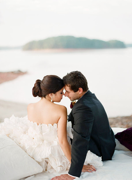 Romantic wedding couple embraces by the sea, heads touching lovingly