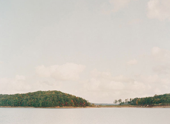Tranquil lake scene with forested islands under a cloudy sky