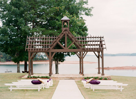 Wedding ceremony venue with a lake view, wooden arch, and benches