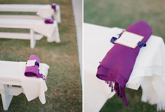 Purple shawls with ribbons and tags on white benches outdoors