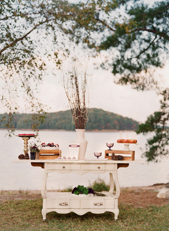 Elegant outdoor dessert table setup near lake with decor