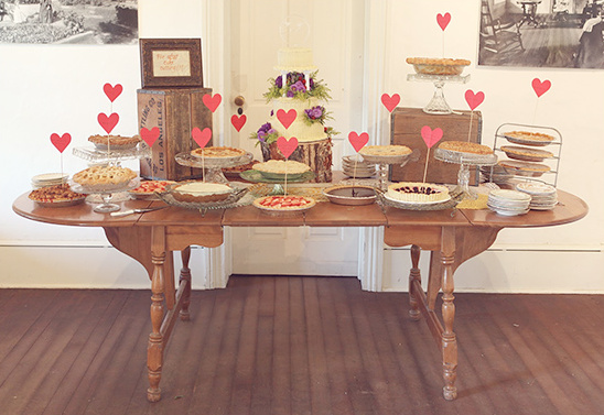 A beautiful pie and cake table decorated with heart toppers