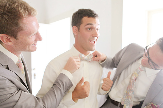 Groomsmen helping groom with his bow tie on wedding day