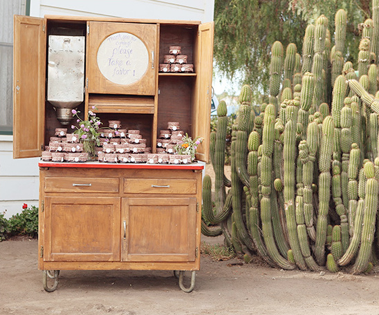 Rustic cabinet filled with treats, with cactus in the background