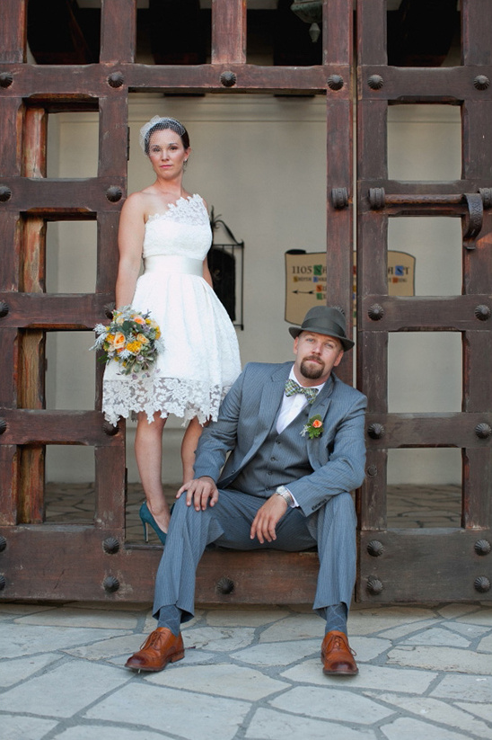 Stylish bride and groom pose by wooden gate