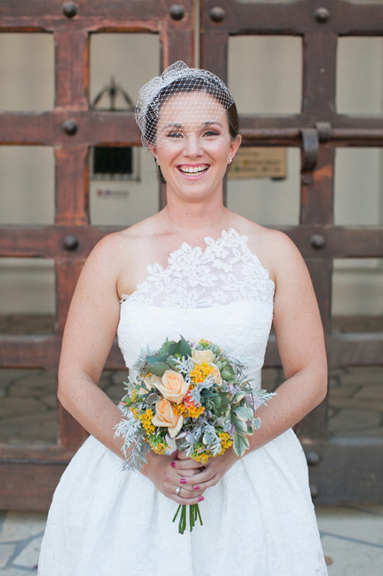 Smiling bride in white dress holds bouquet
