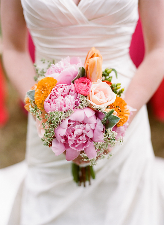 Bride holding a beautiful colorful wedding bouquet of peonies