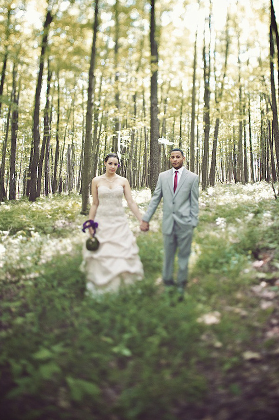 Newlyweds holding hands walking through a forest on their wedding day
