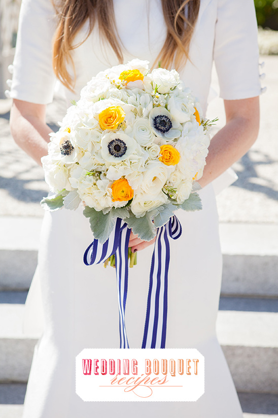 Bride holding beautiful white and yellow wedding bouquet with blue ribbons