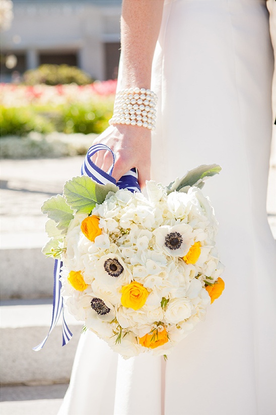 Bride holding a vibrant wedding bouquet with white and yellow flowers