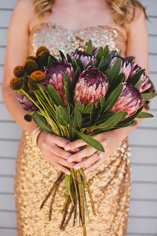 Bride holding Protea flowers, wearing golden sequin dress