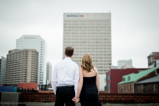 Couple holding hands looking at city buildings from a rooftop