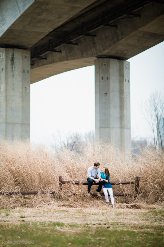 Couple sits and connects under a bridge in tall grass