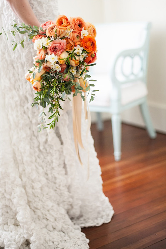 Bride holding a vibrant orange and peach wedding bouquet
