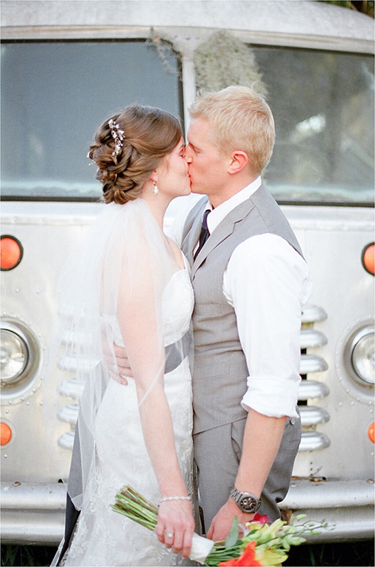Newlyweds kissing tenderly in front of a vintage bus