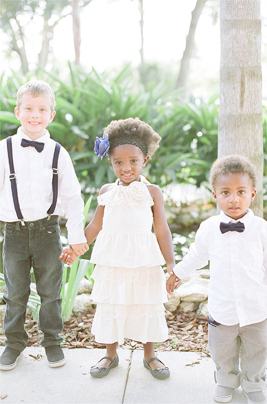 Three children holding hands dressed in formal attire