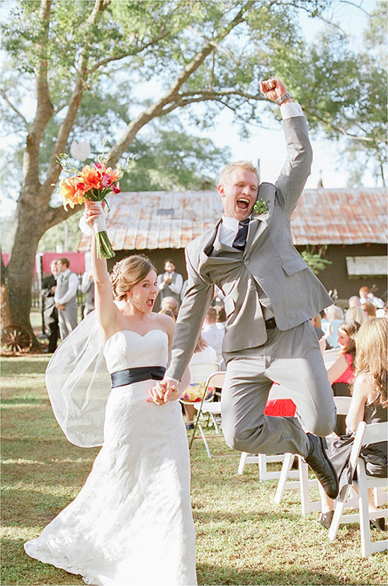Newlyweds joyfully jump after their outdoor wedding ceremony