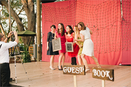 Bridesmaids pose for wedding photos at guest book station