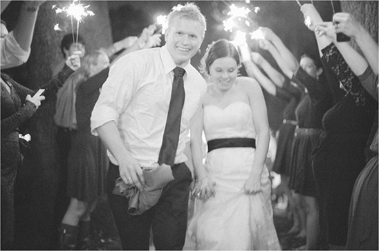 Newlyweds walk through sparklers at their wedding celebration