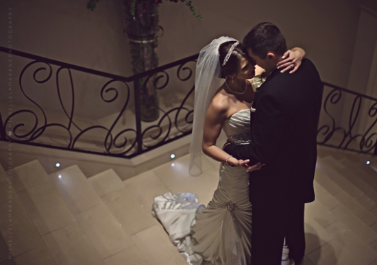 Bride and groom embrace tenderly on wedding day stairs