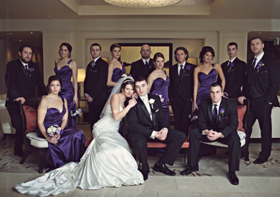 Wedding party posing elegantly in black suits and purple dresses