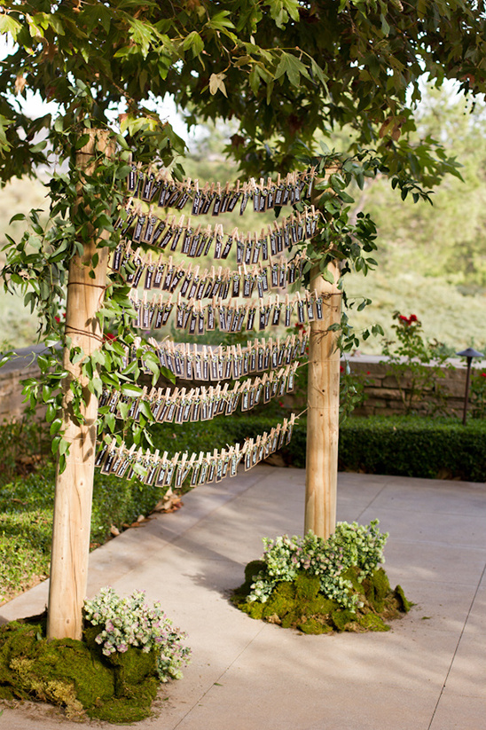 Wedding place cards hanging on a wooden structure in a garden setting