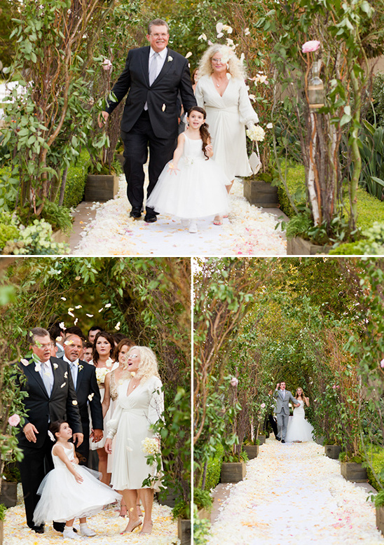 Wedding procession walking through floral archway on a white carpet
