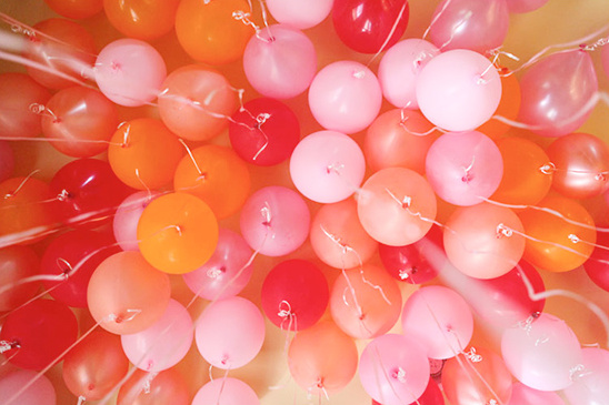 A colorful arrangement of pink, red, and orange balloons