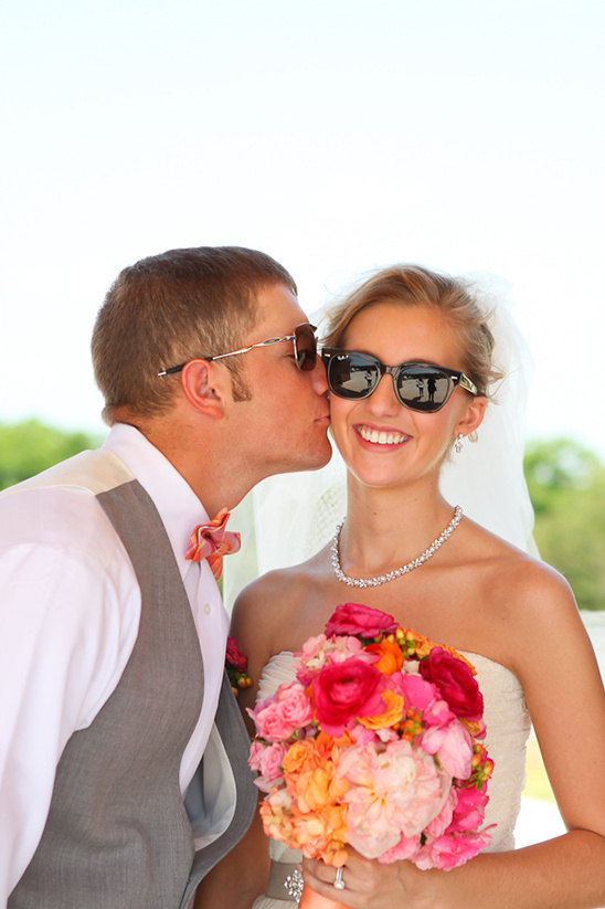 Groom kissing bride holding colorful wedding bouquet