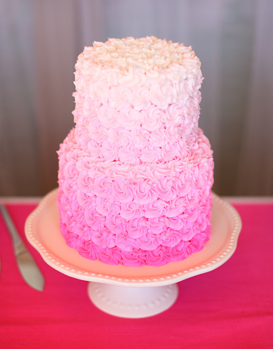 Two-tiered pink ombre frosted cake on a white cake stand