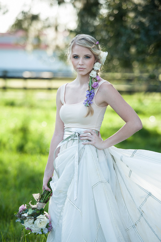 Elegant bride with floral hair piece and flowing dress in a field