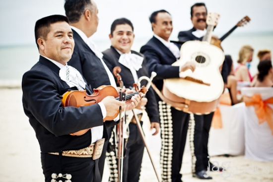 Mariachi band playing music on a beach during a ceremony