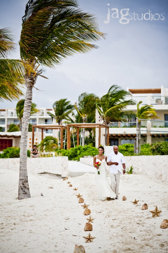 Bride walks down beach aisle with father during tropical wedding