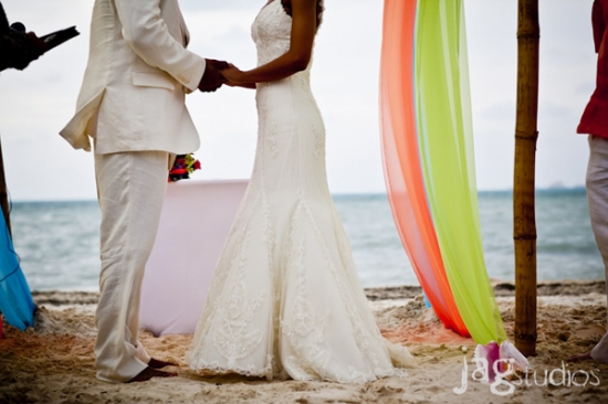 Couple holding hands during a beach wedding ceremony