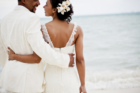 Happy couple in wedding attire on the beach embracing
