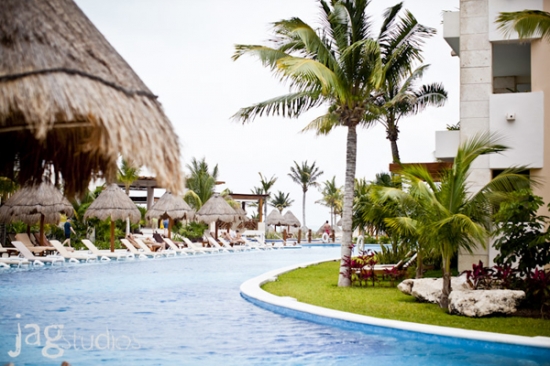 Tropical resort pool with palm trees and thatched umbrellas