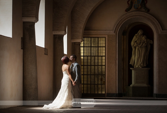 Romantic wedding kiss in a historic building hallway