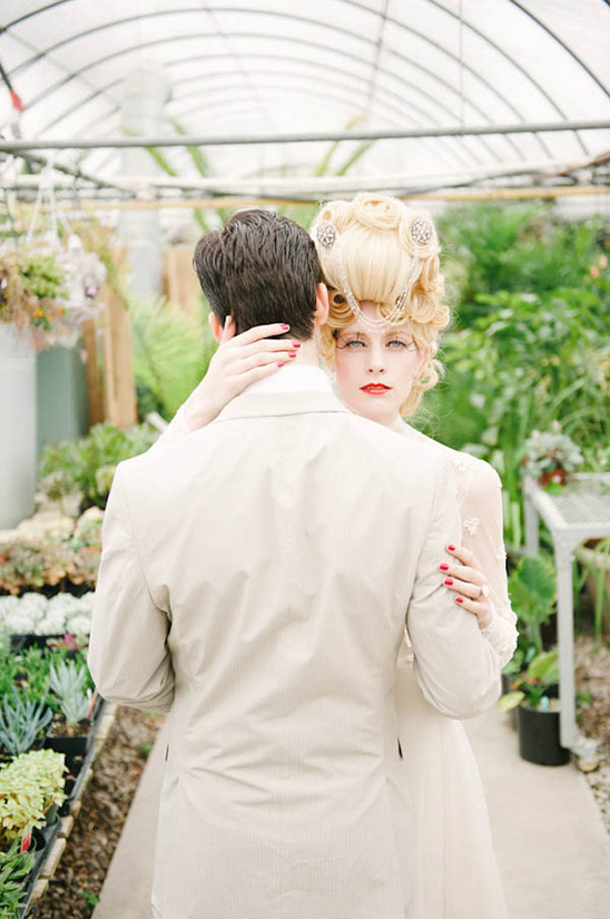 Elegant bride embraces groom in greenhouse setting