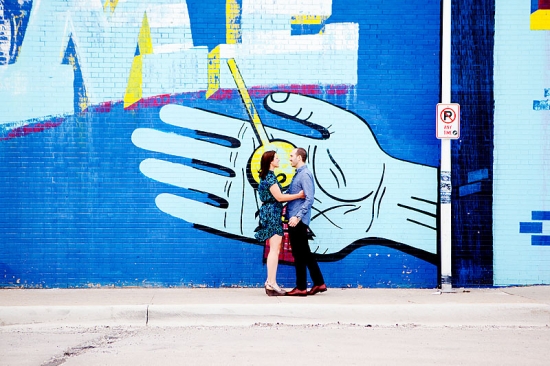 Couple posing by a vibrant blue graffiti wall
