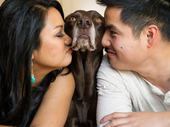 Couple kissing their dog in a loving family portrait