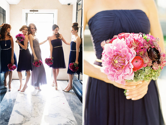 Bridesmaids in navy dresses hold vibrant pink bouquets