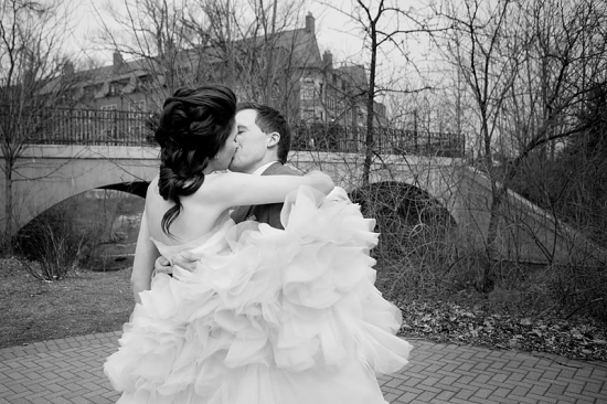 Bride and groom share a tender kiss near a bridge