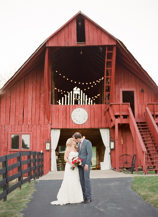 Couple kissing in front of red barn