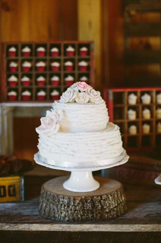 Rustic wedding cake with white roses on wood slice stand