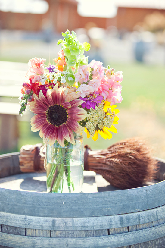 Colorful wildflower bouquet in a mason jar on a barrel