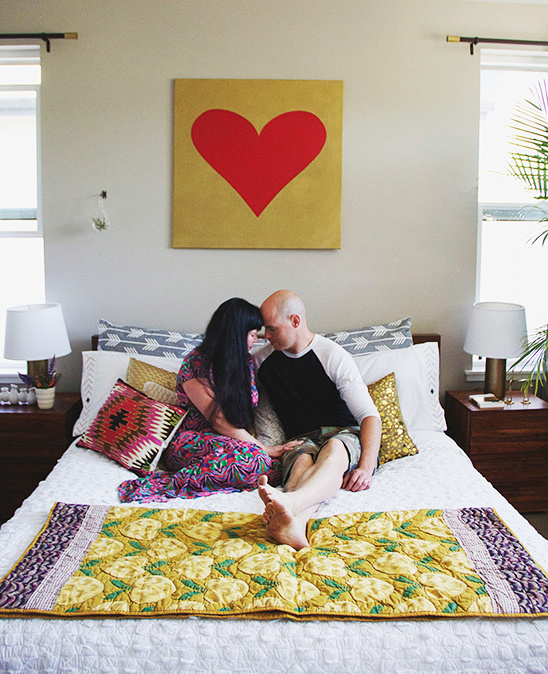Couple cuddling on bed with heart art