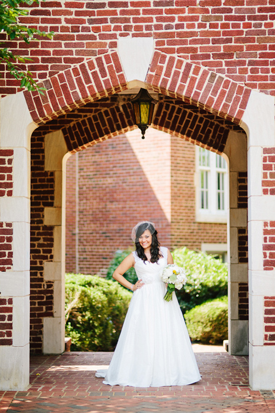 Bride in white wedding dress posing under brick archway