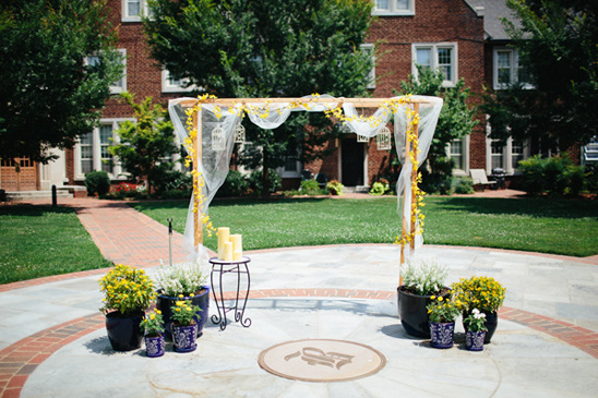 Wedding ceremony arch with yellow flowers and candles