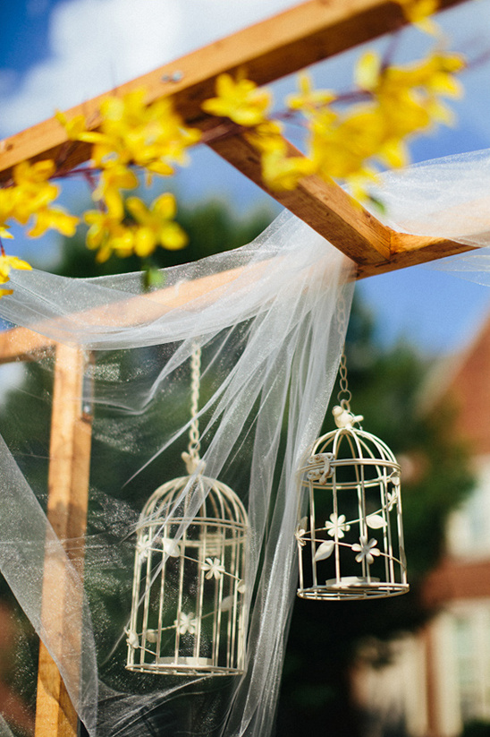 Wedding arch with birdcages and yellow flowers