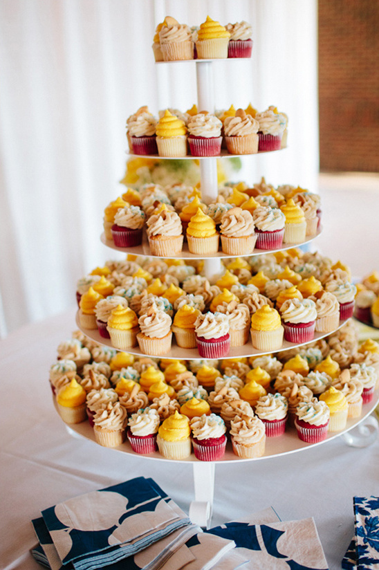 Multi-tiered cupcake tower with yellow, beige, and red frosting